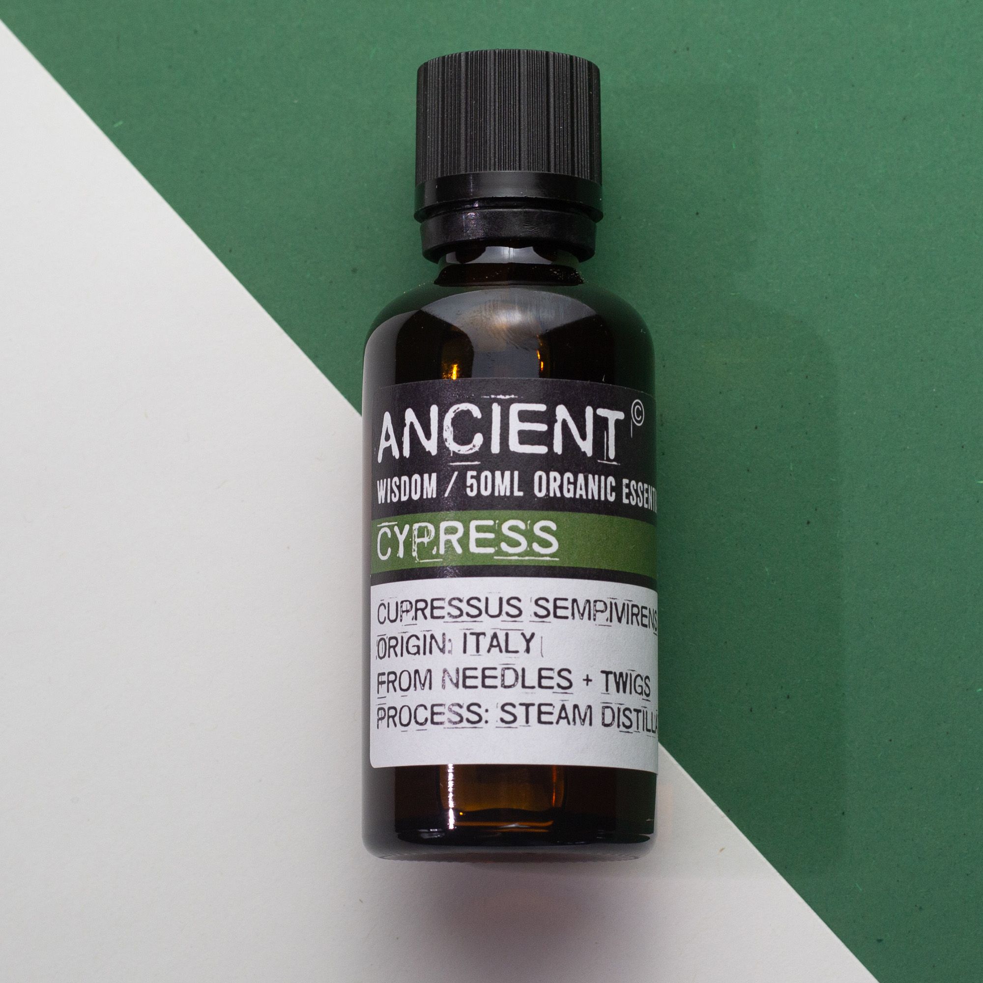 Frasco de aceite esencial orgánico de ciprés 50 ml sobre fondo blanco y verde.