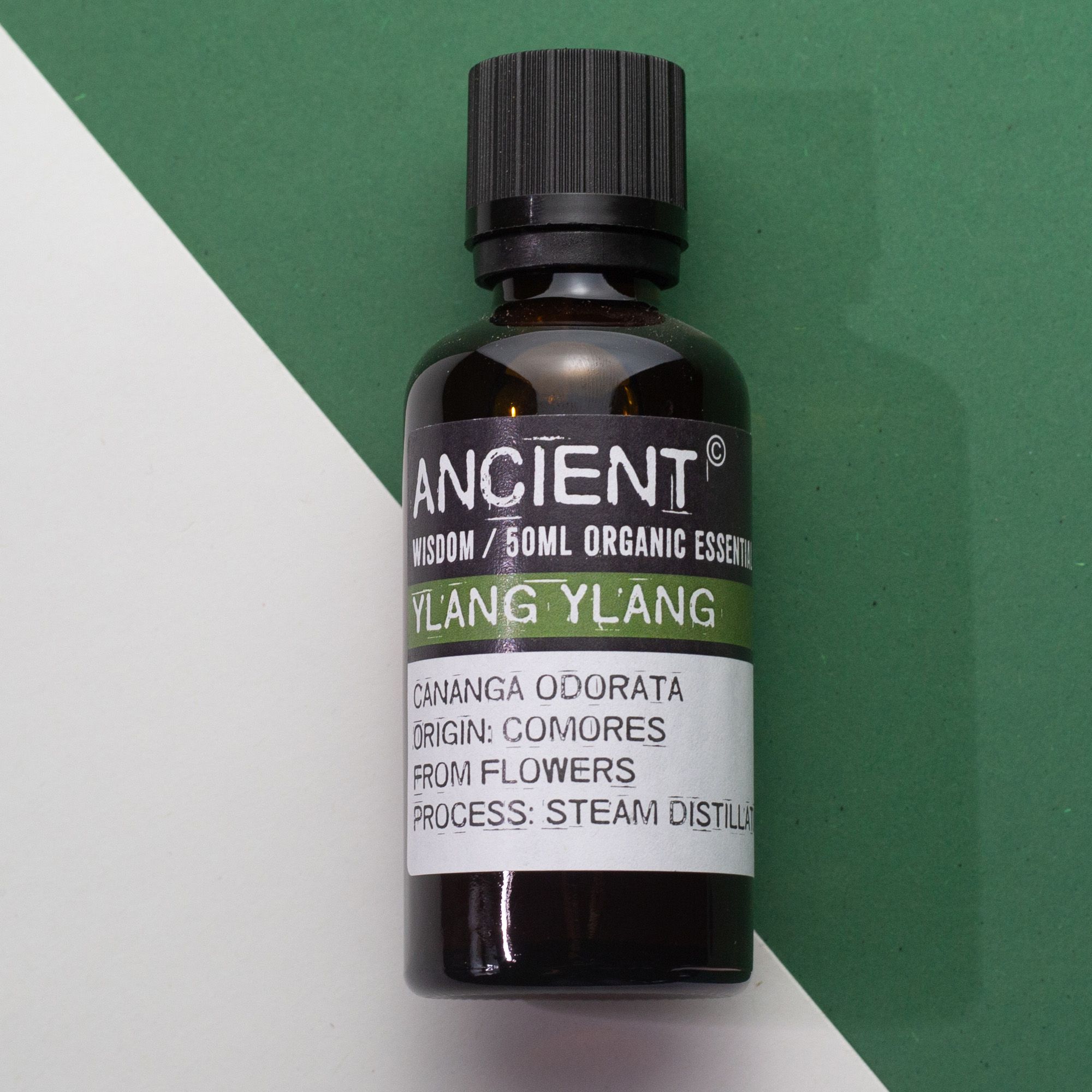 Frasco de aceite esencial orgánico de ylang ylang 50 ml sobre fondo blanco y verde.