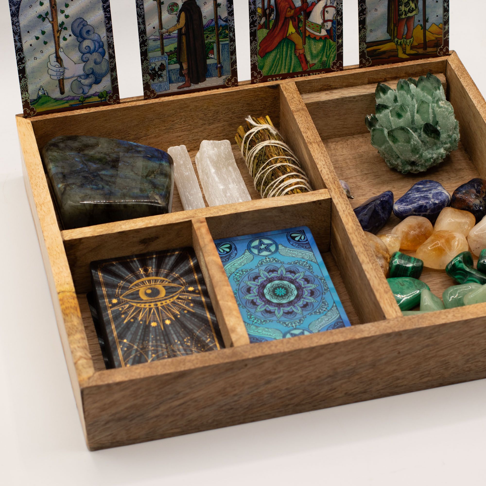 Caja de tarot de madera abierta con cuatro compartimentos que contienen cartas y piedras