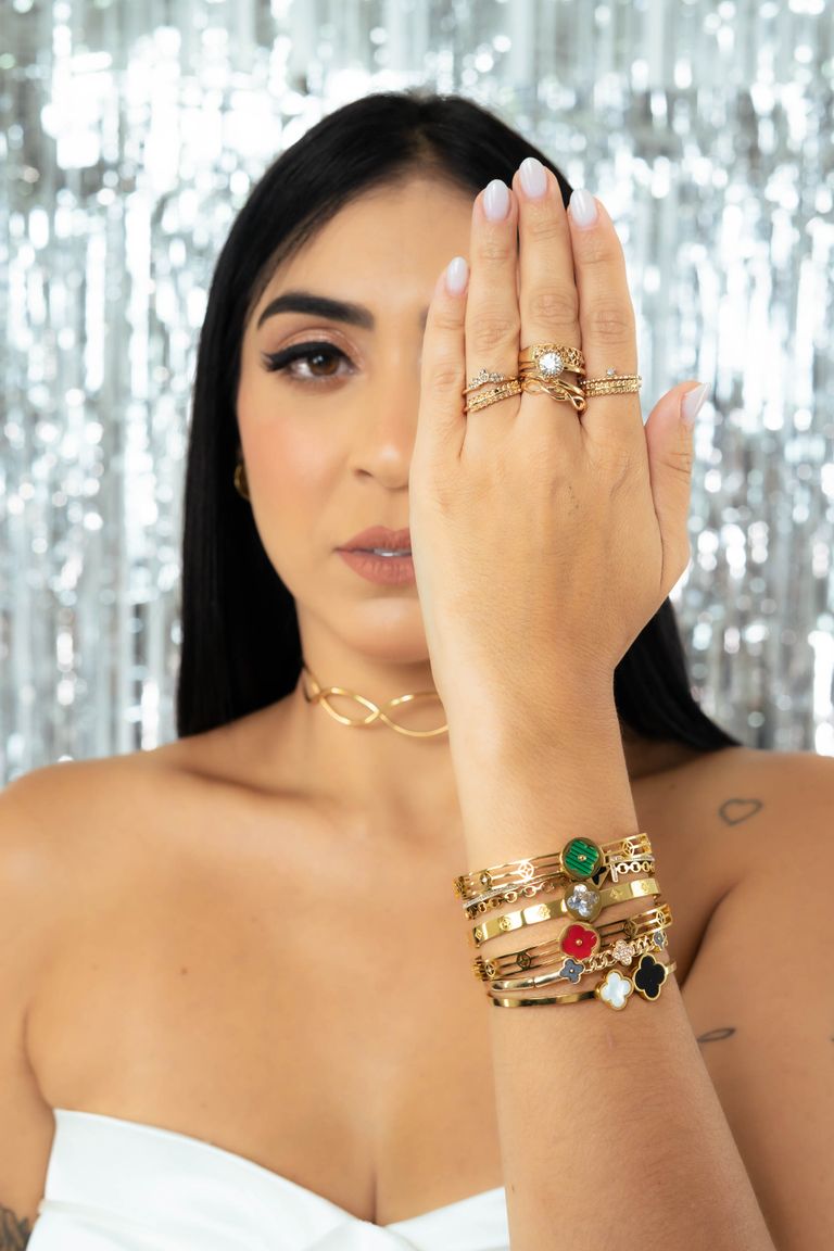Pulseras y anillos dorados sobre fondo luminoso