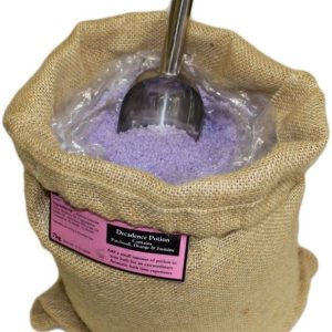 Poción de baño de aromaterapia Energética en un saco abierto con sales de tono violeta y cuchara.