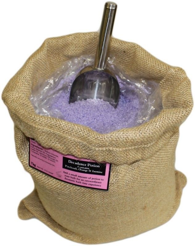 Poción de baño de aromaterapia Energética en un saco abierto con sales de tono violeta y cuchara.
