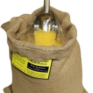 Poción de baño de aromaterapia Estimulante en un saco abierto con sales amarillas y cuchara.