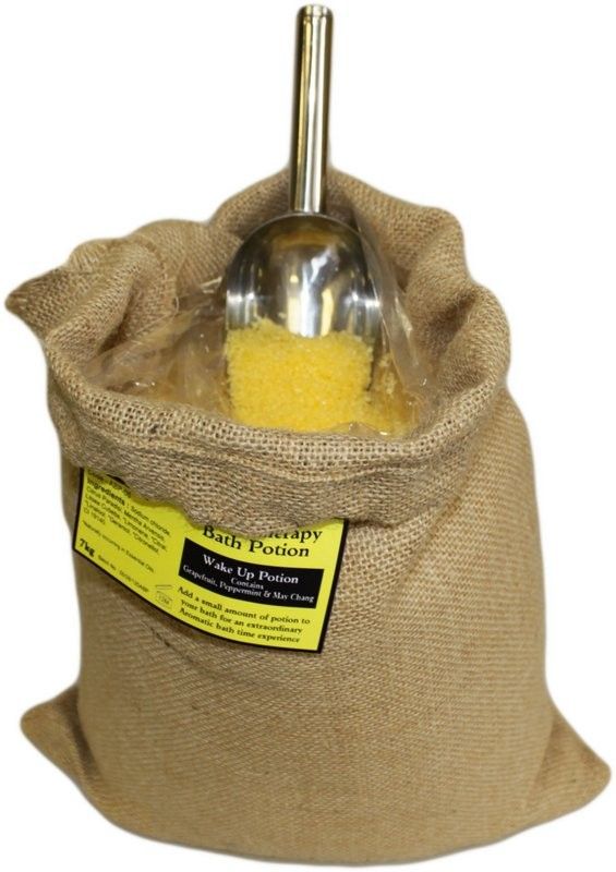 Poción de baño de aromaterapia Estimulante en un saco abierto con sales amarillas y cuchara.
