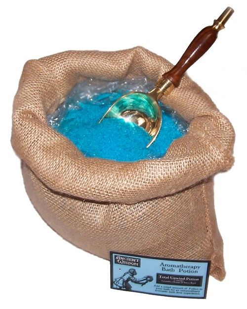 Poción de baño de aromaterapia Relajante en un saco abierto con sales de color azul y cuchara.