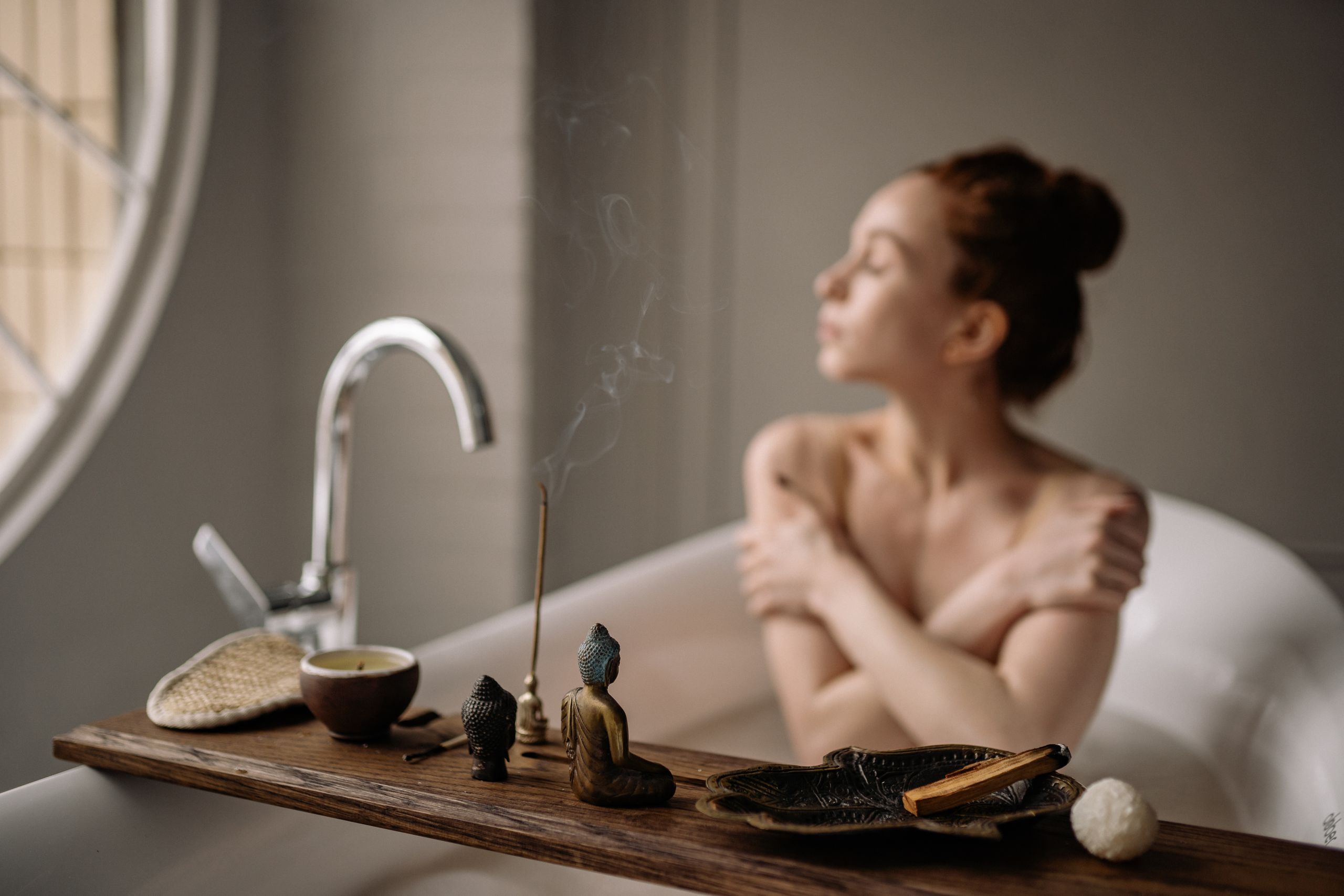 Una escena serena de baño que muestra a una mujer disfrutando de un momento de relajación con incienso y una taza de té caliente.