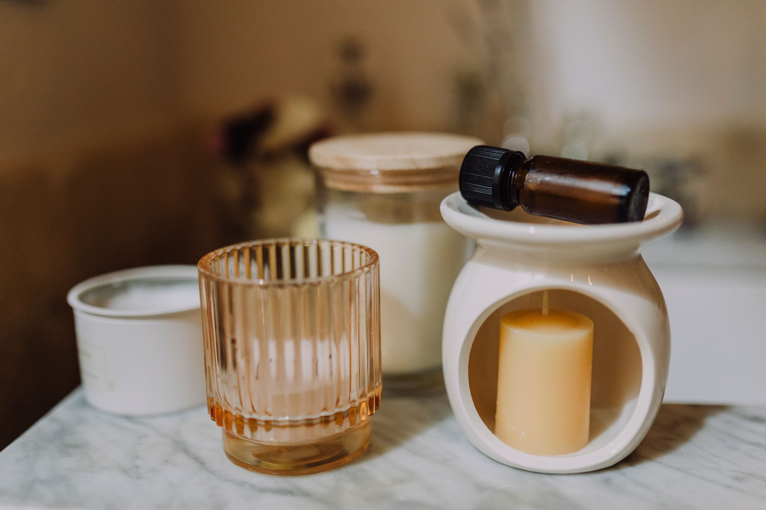 composición de aromaterapia con velas, frascos de vidrio y aceite esencial sobre mármol.